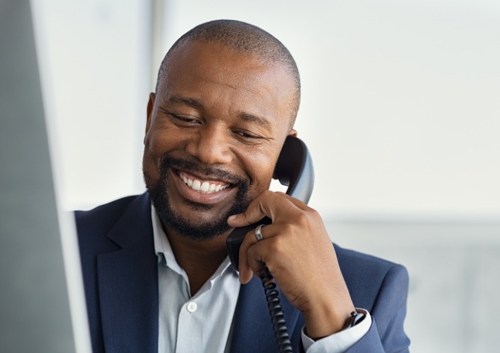 A well dressed man smiling while being on the phone